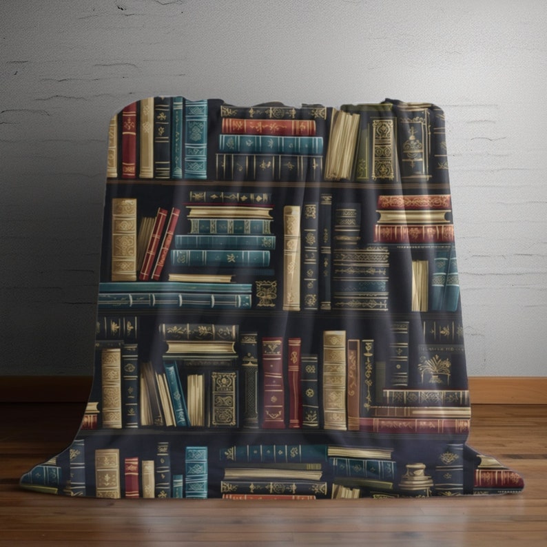 May include: A black and white throw blanket with a repeating pattern of books on a bookshelf. The books are in various colors, including red, blue, green, and gold. The blanket is made of a soft, comfortable material.