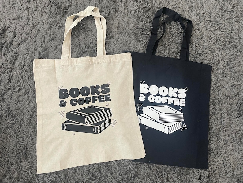 以下が含まれることがあります： 黒と白で「Books & Coffee」と印刷されたトートバッグ2つ。バッグはキャンバス製で、黒いハンドルが付いています。