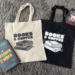 以下が含まれることがあります： 「Books & Coffee」と印刷されたトートバッグが2つあります。1つのバッグは白地に黒文字、もう1つは黒地に白文字です。両方のバッグには、コーヒーカップが置かれた本が積み重ねられています。白いバッグの隣には、「The Butcher and the Wren」というタイトルのAlaina Urquhartの本があります。