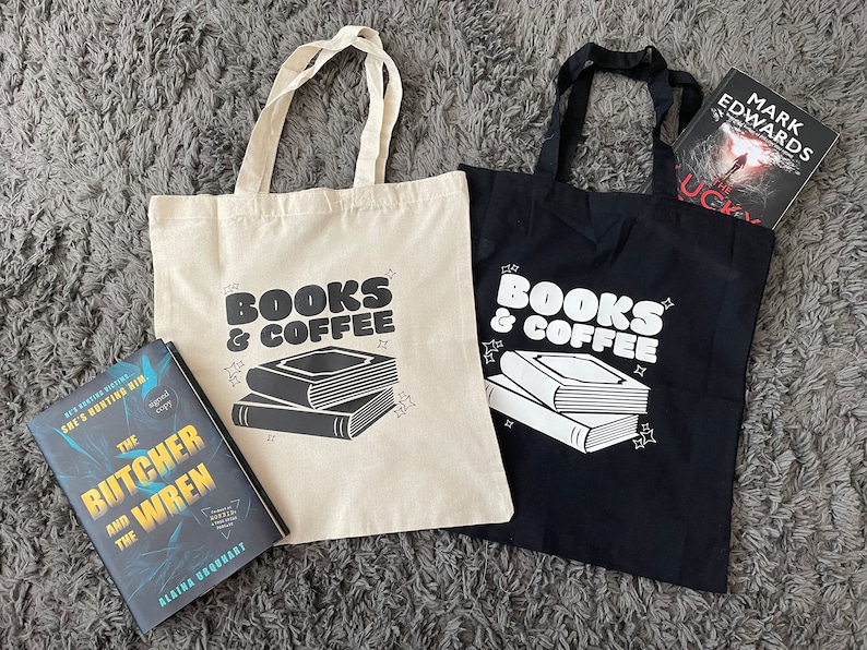 以下が含まれることがあります： 「Books & Coffee」と印刷されたトートバッグが2つあります。1つのバッグは白地に黒文字、もう1つは黒地に白文字です。両方のバッグには、コーヒーカップが置かれた本が積み重ねられています。白いバッグの隣には、「The Butcher and the Wren」というタイトルのAlaina Urquhartの本があります。