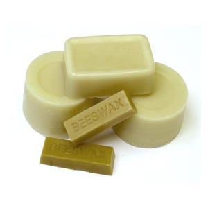 May include: A selection of beeswax blocks in different forms. The blocks are a pale yellow hue, with rectangular and circular shapes. Two smaller blocks are inscribed with the word "BEESWAX".