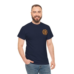 May include: Navy blue t-shirt featuring a gold-colored firefighter emblem on the left chest. The emblem includes a Maltese cross design with a fleur-de-lis in the center. The shirt is a classic crew neck style.