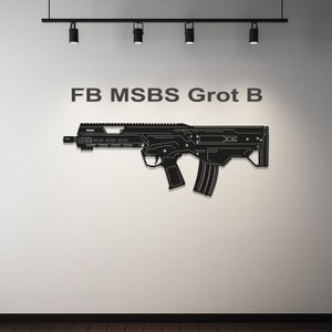 May include: Black metal wall art of a rifle, mounted on a white wall. The rifle is a detailed silhouette with the text "FB MSBS Grot B" above it. The art is illuminated by track lighting.