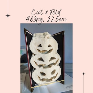 May include: A book folded into the shape of three stacked jack-o'-lanterns. The book is open and the pages are folded to create the shape of the pumpkins. The book is 463 pages and 22.5 cm tall.