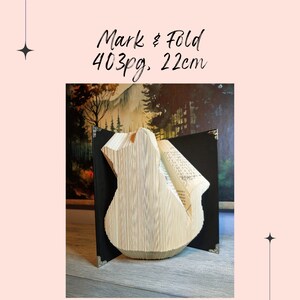 May include: A book folded into the shape of a bird, standing on a black book with a brown background. The book is marked "Mark & Fold 403pg. 22cm".