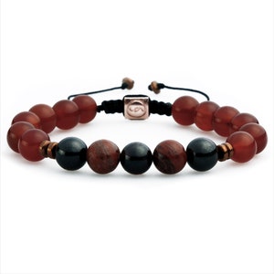 May include: A beaded bracelet with red carnelian and black onyx beads. The bracelet has a black cord with a silver clasp.