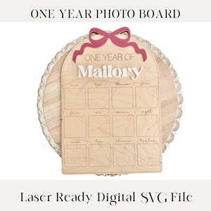 May include: A wooden photo board with a white lace border and a red bow. The board has 12 spaces for photos, labeled with the numbers one through twelve. The board also has the text "One Year of Mallory" on it.