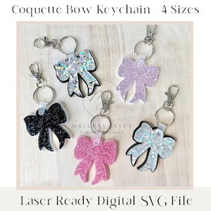 May include: Five different glitter bow keychains in various colours, including black, pink, silver, and purple. Each keychain features a silver metal ring and a silver clasp. The keychains are displayed on a light wood surface. Coquette Bow Keychain - 4 Sizes. Laser Ready Digital SVG File.