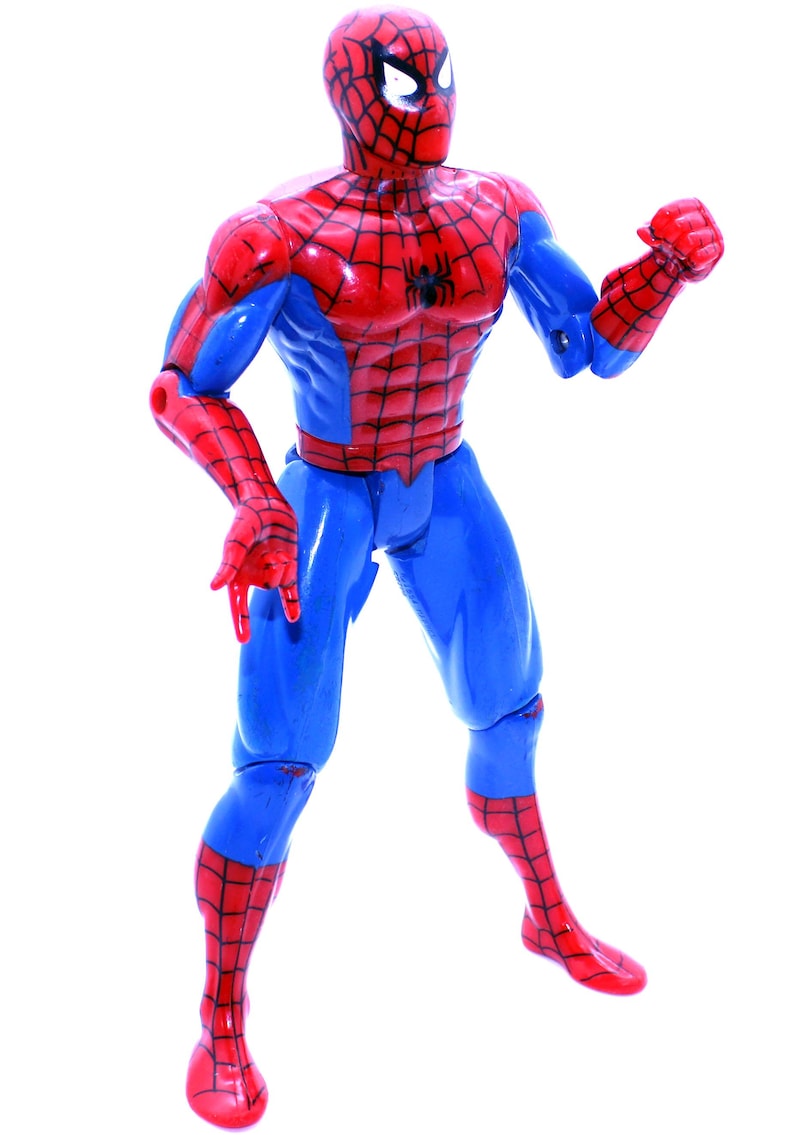 May include: A red and blue plastic action figure of Spider-Man. The figure has a web design on the chest and legs. The figure is posed with one arm raised and the other arm bent at the elbow.