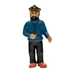 May include: A figurine of a sailor in a blue sweater with anchor details, black pants, and red shoes. The sailor wears a black hat with a gold emblem and holds a pipe. The figurine has a black beard and mustache.