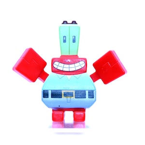 Pode incluir: Uma figura de brinquedo vermelha e azul de um caranguejo de desenho animado com um grande sorriso. O caranguejo tem grandes garras vermelhas e uma cabeça verde com dois olhos brancos.