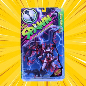 Op de afbeelding: Een Spawn Widow Maker actiefiguur in de originele verpakking. Het figuur heeft een zwart en rood kleurenschema met grote vleugelachtige aanhangsels, een klein vleermuisachtig wezen en tekst waaronder Spawn, Todd McFarlane en 20 Points of Articulation.