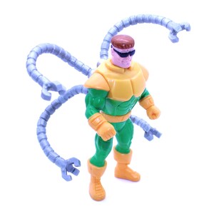 May include: A Dr. Octopus action figure. The figure is wearing a yellow and green outfit with four articulated mechanical arms. The figure has a brown head and is wearing black sunglasses. The figure is standing on a white surface.