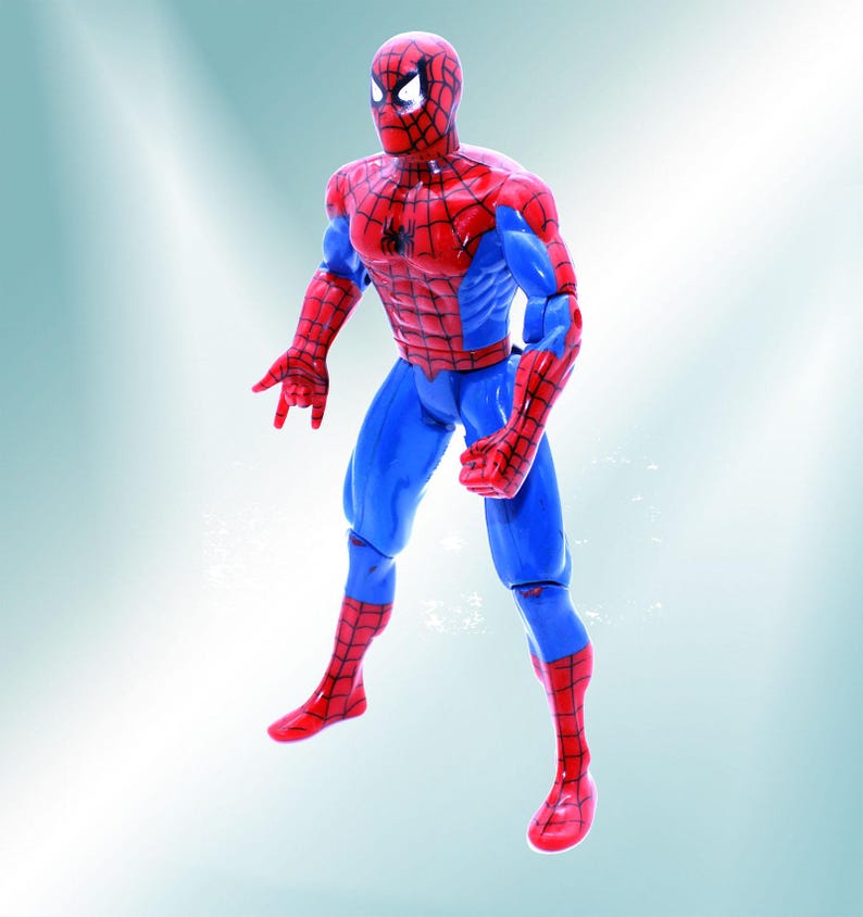 May include: A red and blue action figure of Spider-Man with a black spider logo on the chest. The figure is posed in a dynamic stance with one arm raised and the other bent at the elbow.