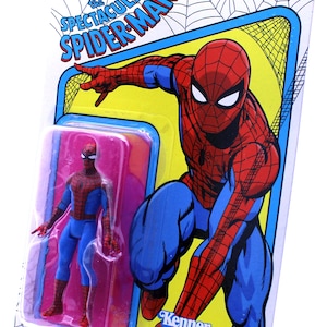 Pu&ograve; includere: Una action figure vintage Kenner Marvel Legends di Spider-Man in una confezione blister di plastica. La figura &egrave; rossa e blu con un simbolo di ragno nero sul petto. La confezione presenta uno sfondo giallo e blu con le parole "The Spectacular Spider-Man" e "Kenner".