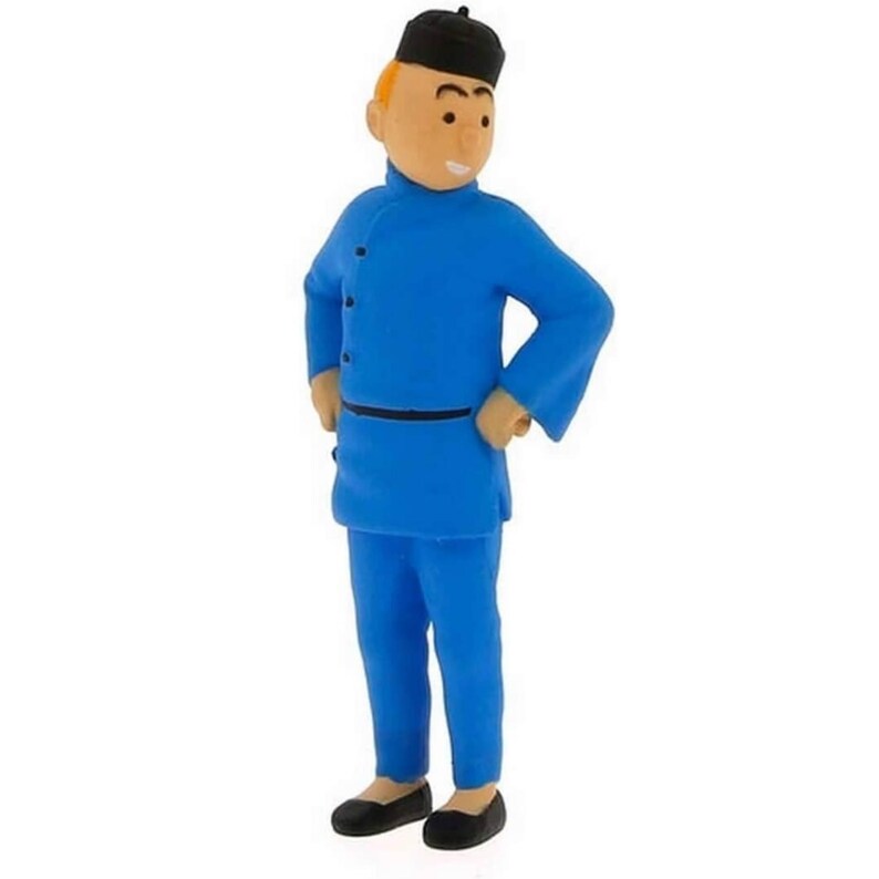 May include: A figurine of a character in a blue outfit with a black hat and shoes. The figure has a light skin tone and is standing with hands on hips. The outfit includes a long-sleeved tunic and matching trousers.