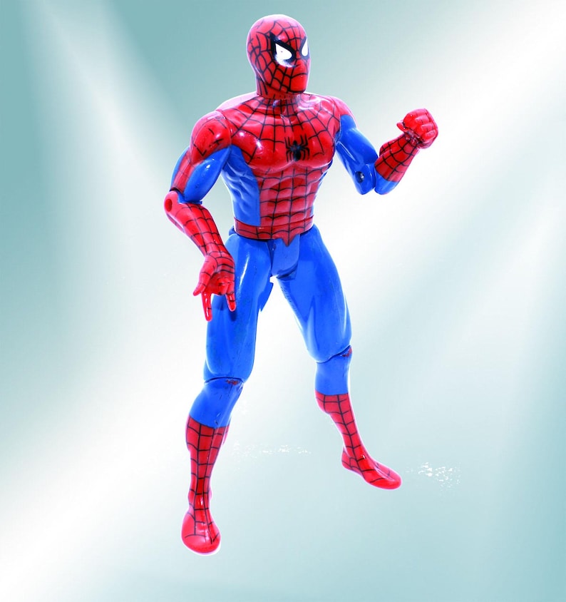 May include: A red and blue action figure of Spider-Man with a web design on his chest and legs. The figure is posed with one arm raised and a fist clenched.