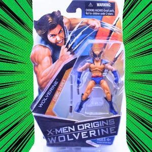 Może przedstawiać: Figurka Wolverine w przezroczystym plastikowym opakowaniu. Figurka jest żółto-niebieska, z maską i pazurami. Opakowanie zawiera tekst "Wolverine Comic Series" i "X-Men Origins Wolverine". Opakowanie zawiera również ostrzeżenie o małych częściach.