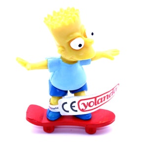 Könnte beinhalten: Eine gelbe Plastikfigur von Bart Simpson aus den Simpsons, trägt ein blaues Hemd und blaue Shorts, fährt auf einem roten Skateboard mit einem weißen Aufkleber, auf dem "CE yolanda" steht.