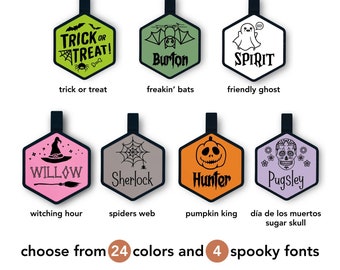 May include: Eight different Halloween-themed designs for personalized tags. The designs include a trick or treat pumpkin, a friendly ghost, a spider web, a witch's hat, a sugar skull, a pumpkin, a bat, and a skull. The text "choose from 24 colors and 4 spooky fonts" is at the bottom of the image.
