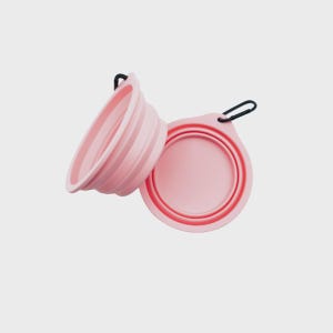 May include: Two light pink collapsible bowls made of flexible silicone. Each bowl features a circular base, ribbed sides for folding, and a small tab with a black metal carabiner attached for easy carrying and storage during travel or outdoor use.