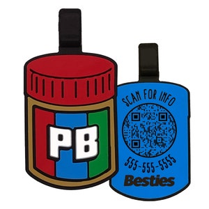 May include: Two blue and black plastic keychains. One keychain features a peanut butter jar with the letters "PB" on the label. The other keychain has a QR code and the text "SCAN FOR INFO", "555-555-5555", and "Besties".