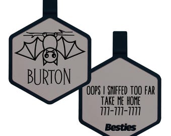 May include: Two hexagonal pet tags. One tag features a bat graphic with the name "BURTON". The other tag has the text "OOPS I SNIFFED TOO FAR TAKE ME HOME 777-777-7777 Besties". Both tags have a gray center and a dark blue border.