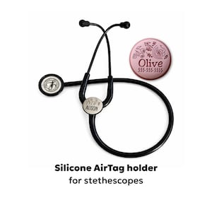 May include: Black stethoscope with a round, white tag that says "Alison" and a pink AirTag holder with the name "Olive" and a phone number. The text at the bottom says "Silicone AirTag holder for stethoscopes."