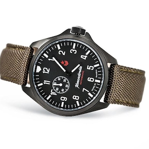 Puede incluir: Un reloj de pulsera negro con una correa de lona marrón. La esfera del reloj tiene marcas blancas y una estrella roja con el texto "Komandirskie AUTOMATIC MADE IN RUSSIA".