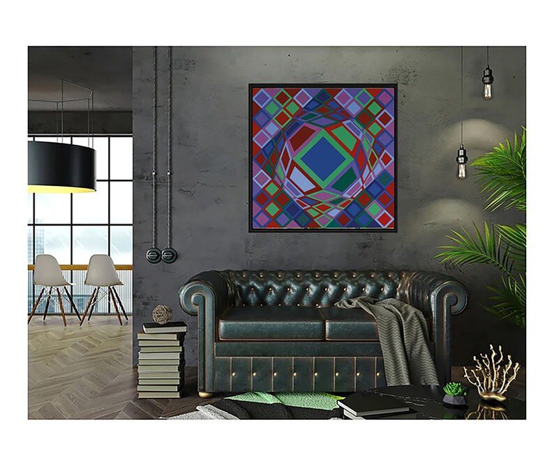 May include: A framed abstract geometric art piece with a black frame, featuring a colorful design of squares and a central sphere. The artwork hangs above a dark green leather sofa in a modern living room setting.