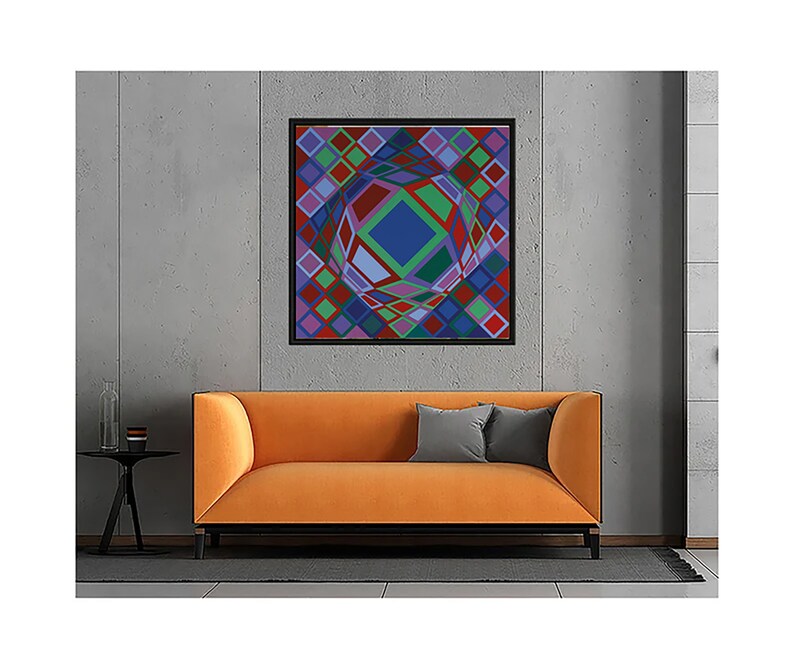 May include: An abstract geometric artwork in a black frame hangs above an orange sofa. The artwork features a central blue diamond shape surrounded by colorful diamond patterns in red, green, purple, and blue. A small black side table and gray pillows complete the scene.