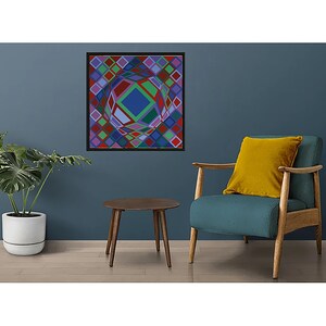 May include: A framed abstract geometric art print with a black frame. The artwork features a colorful, three-dimensional design with squares and diamond shapes in shades of red, green, blue, and purple. The art is displayed on a dark blue wall.