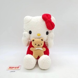 May include: A plush white cat-like character with a red dress and bow, holding a small brown teddy bear with a white bow. The character has black eyes and a yellow nose. The plush toy is on a white background.
