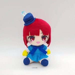 May include: A plush doll with red hair, wearing a blue dress, hat, and shoes. The doll has large, expressive eyes and yellow gloves. The doll is sitting down. The text "U0338" is printed on the bottom.