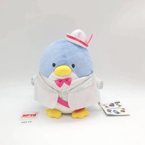 May include: A plush penguin toy with a light blue head, yellow beak, and white tuxedo. The penguin wears a pink bow tie and a small hat with a pink stripe. A tag with the text "KPTD" and "V0116" is attached.