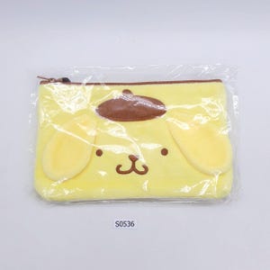 以下が含まれることがあります： 茶色の耳と茶色の帽子が付いた漫画の犬の顔が特徴の、黄色のぬいぐるみジッパーポーチ。ポーチには茶色のジッパーが付いており、透明なプラスチックで包装されています。「S0536」という文字が白いステッカーに印刷されています。