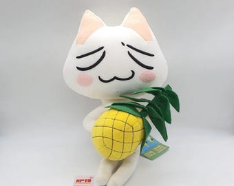 May include: A white plush cat toy with a sad expression, holding a yellow pineapple with green leaves. The cat has pink cheeks and black facial features. A tag is attached to the pineapple.