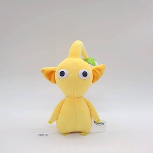 May include: A yellow plush toy character with large black eyes, orange ears, and a curved stem on its head. The toy has small arms and feet. A tag with Japanese text is attached to the toy. The product code U0670 is visible.