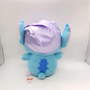May include: A plush toy of a blue alien-like creature with large ears and a small tail. The toy is wearing a lavender satin bonnet. The toy has a tag with the text "KPTB" and the number "E0324".