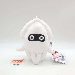 Op de afbeelding: Een witte pluche inktvis met zwarte oogdetails en een label. Het speelgoed heeft een zachte, afgeronde vorm met tentakels en een kleine lus aan de bovenkant. Het label toont een cartoon inktvis illustratie.