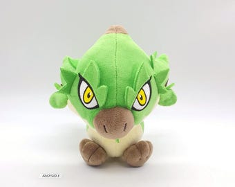 May include: A plush toy in the shape of a green creature with large yellow eyes, brown snout, and small brown feet. The toy has a light green belly and a small brown patch on its head. The tag reads "R0501".