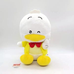 May include: A plush duck toy with a white head and body, a yellow beak, and yellow feet. The duck wears a yellow shirt with a red bow tie. The toy is winking and giving a thumbs-up.