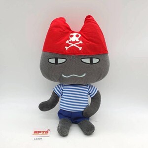 Pode incluir: Um peluche de uma personagem cinzenta semelhante a um gato, usando uma bandana de pirata vermelha com um emblema branco de caveira e ossos cruzados. A personagem tem uma camisola às riscas azuis e brancas e calções azuis, com etiqueta KPTD L0339.