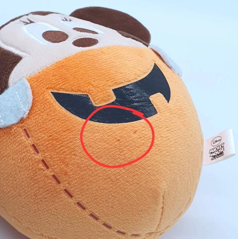 K&ouml;nnte beinhalten: Ein Pl&uuml;schtier in K&uuml;rbisform mit einem braunen Mickey-Maus-Kopf oben. Der orangefarbene K&uuml;rbisk&ouml;rper hat ein schwarzes Jack-o'-Lantern-Gesicht und einen kleinen roten Kreis auf der Oberfl&auml;che. Ein wei&szlig;es Etikett zeigt Disney Mickey Mouse & Friends.