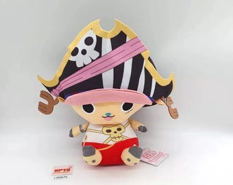 May include: A plush toy character with a pirate hat featuring a skull and crossbones design. The toy has a tan face, a pink visor, and a red and white outfit. The toy is a collectible item.