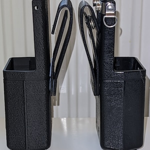 May include: Two black plastic tool holders with belt loops. Each holder has a textured surface and a metal clip.