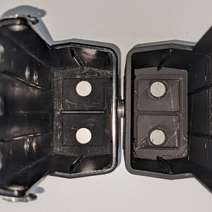 May include: Two black plastic cases with a hinge. Each case has two circular openings. The cases are open and the openings are visible.