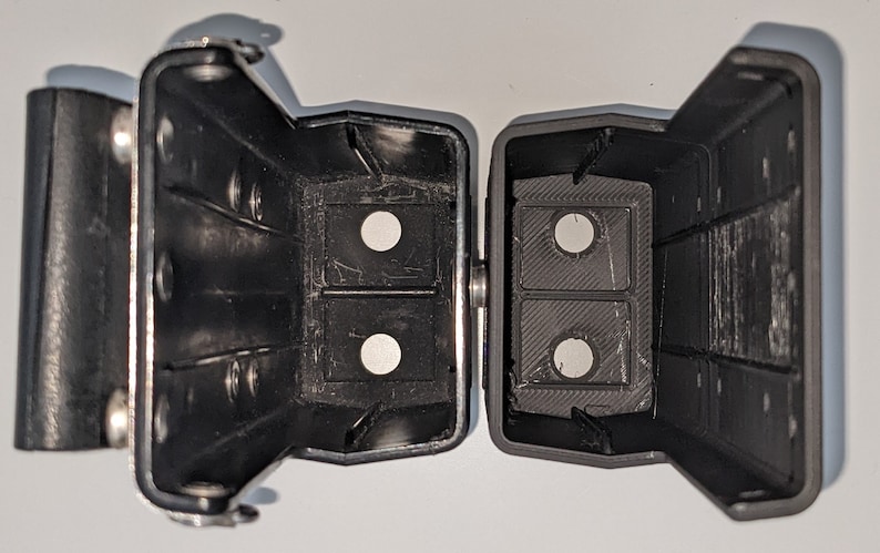 May include: Two black plastic cases with a hinge. Each case has two circular openings. The cases are open and the openings are visible.