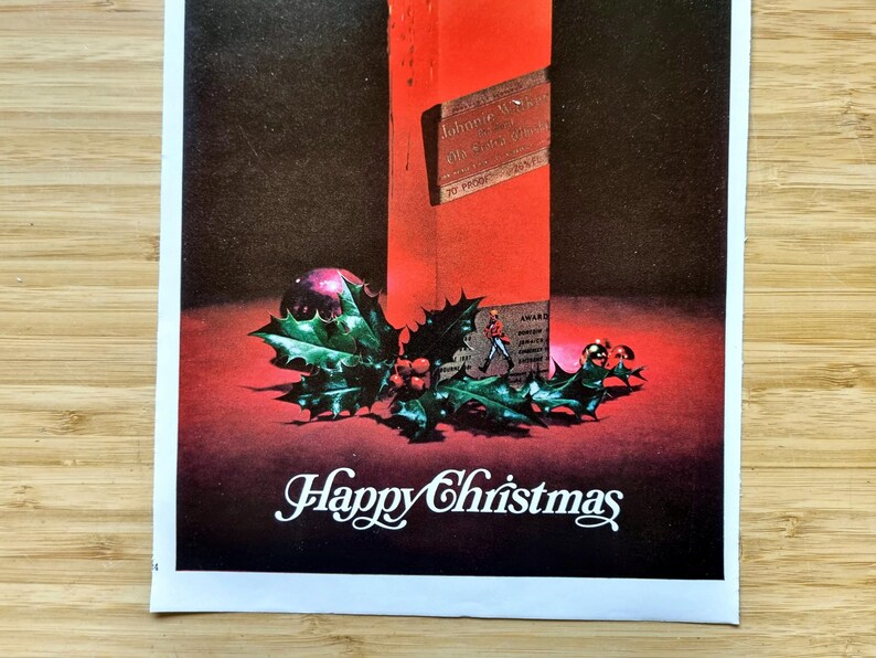 May include: A vintage Christmas advertisement featuring a red bottle, holly, and a purple ornament. The words "Happy Christmas" are written in white script at the bottom. The bottle has a label with text.