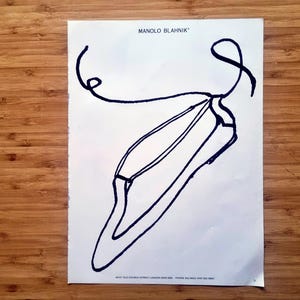 1980s Manolo Blahnik magazine advertisement page showing a bold black line drawing of a pointed-toe shoe with a looping strap on a white background with the Manolo Blahnik name printed at the top.